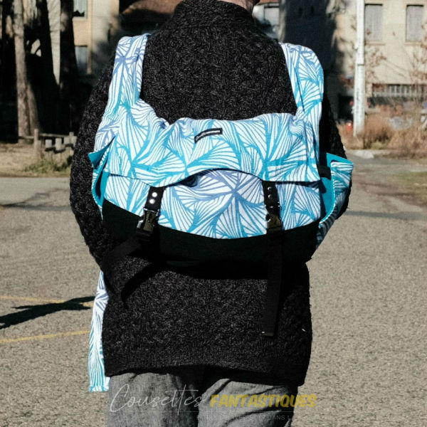 Blue babywearing bag in Backpack style, without baby. Picture taken outside.
